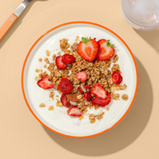 Detailansicht der knusprigen Granola-Mischung Strawberry Almond mit Milch in einer Schüssel.
