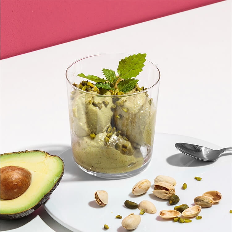 Avocado Pistazien Nicecream mit einer halben Avocado daneben