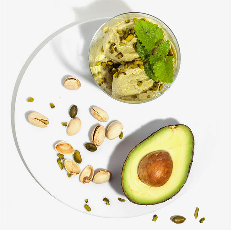 Avocado Pistazien Nicecream mit einer halben Avocado daneben