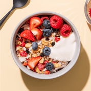 mymuesli Bio Paleo Coconut Nut Crunchy Müsli in Schale mit frischen Himbeeren, erdbeeren und Blaubeeren sowie Joghurt