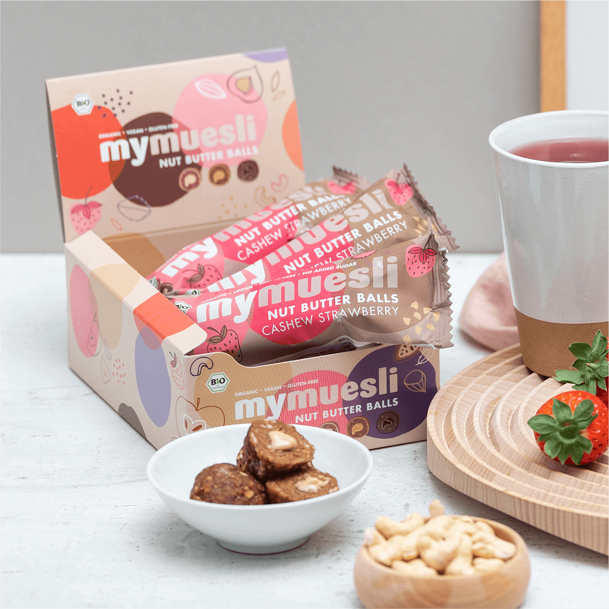 Cashew-Erdbeer Nut Butter Balls angerichtet mit frischen Erdbeeren und Cashewkernen.