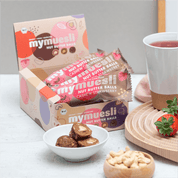 Cashew-Erdbeer Nut Butter Balls angerichtet mit frischen Erdbeeren und Cashewkernen.