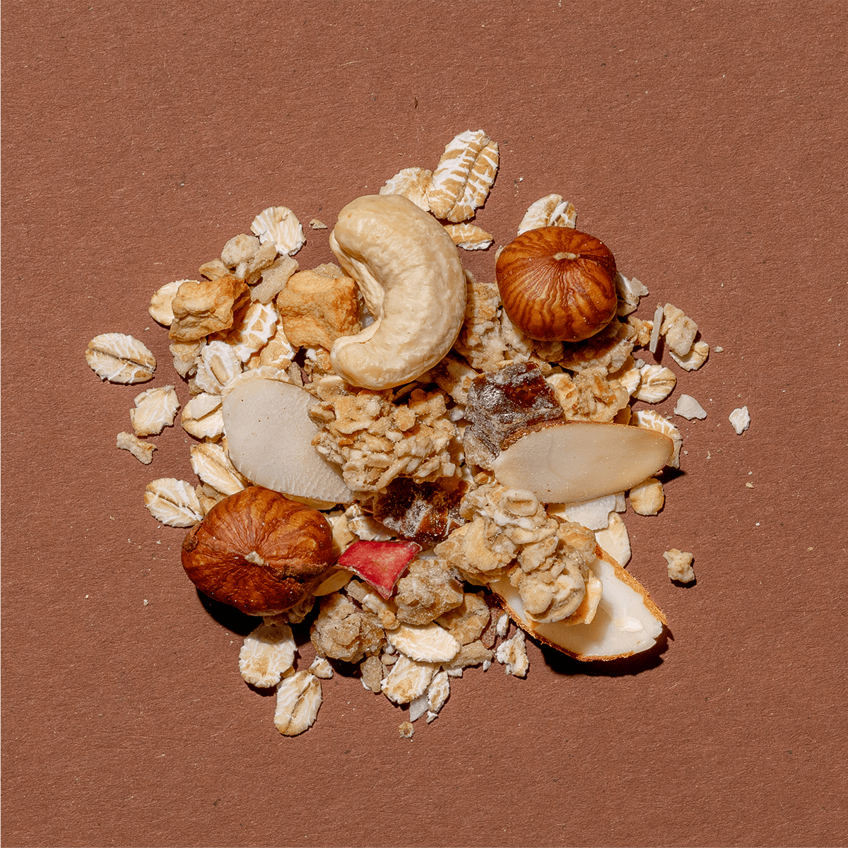 Detailansicht der Honey & Nuts Müsli-Mischung mit Fokus auf ganzen Cashewkernen, Haselnüssen und Haferflocken auf Braun.