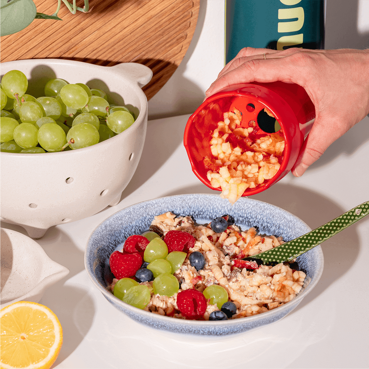 Geriebener Apfel wird von der Apfelreibe auf Bircher gefüllt