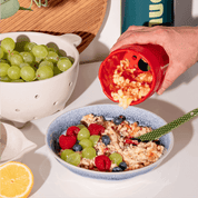 Geriebener Apfel wird von der Apfelreibe auf Bircher gefüllt