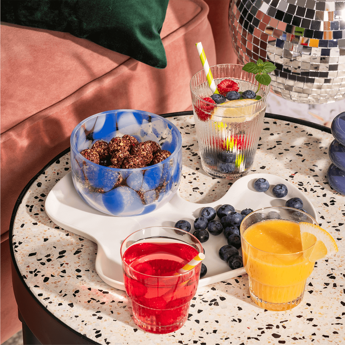 mymuesli Bio Raspberry Dark Choc Crunchy Bites in der Schüssel schön angerichtet mit Beeren und Saft auf dem Tisch