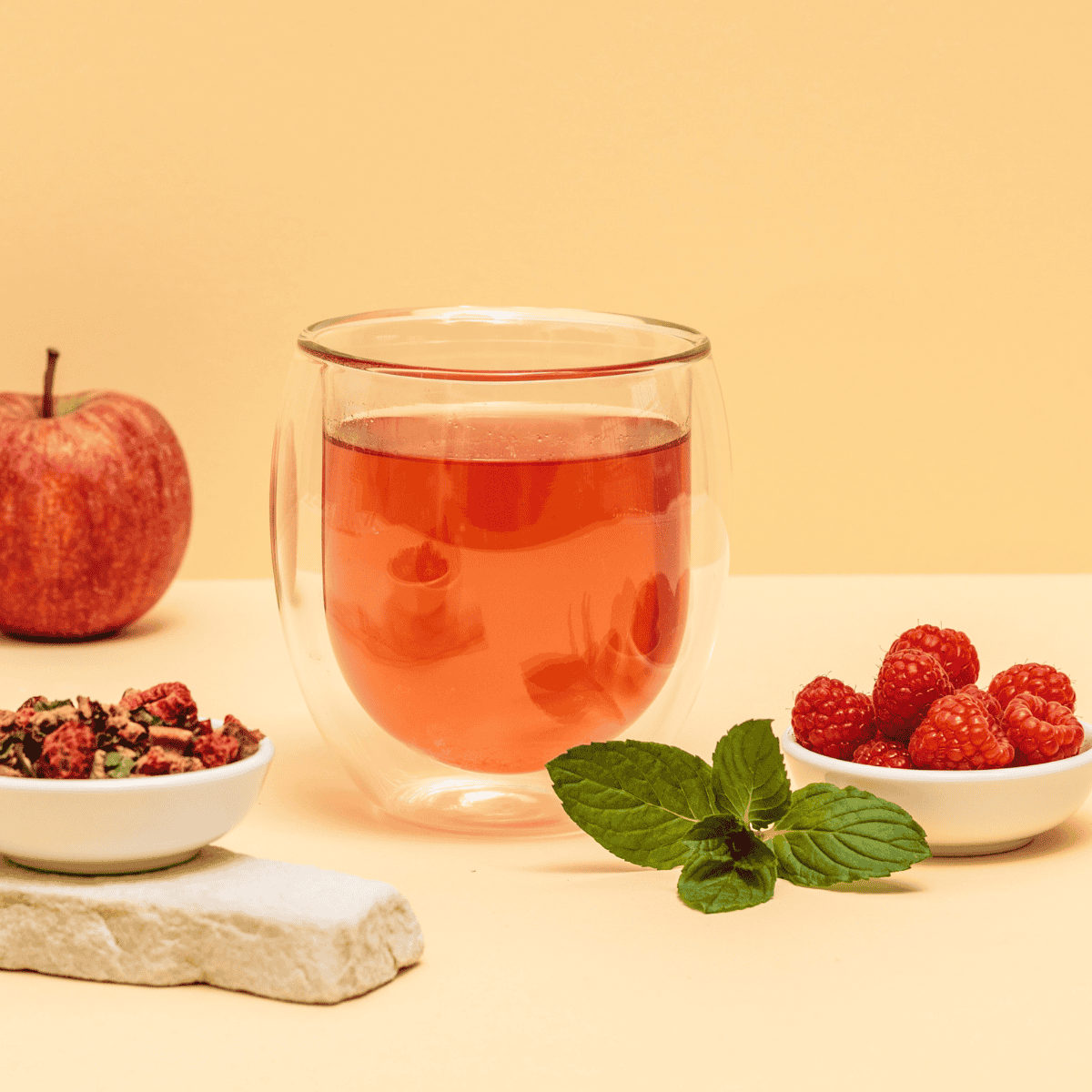 Zubereiteter roter Früchtetee in einer Glastasse neben der Red Ruby Dose.
