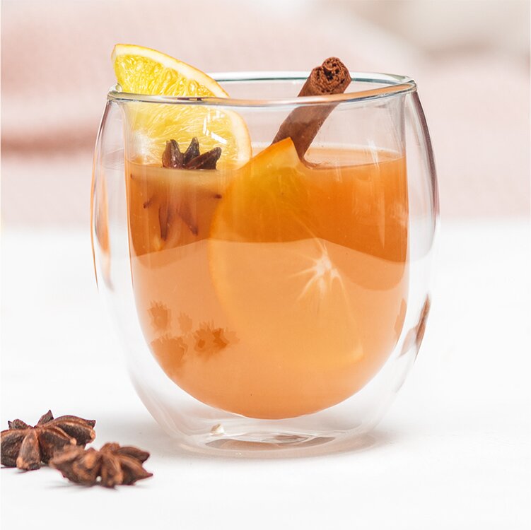 Glory's Chai Punsch in einem Glas mit Gewürzen und Orangenscheiben